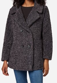 Double-breasted gray coat with a textured, fuzzy surface, large lapel, and black buttons, paired with a dark top and blue jeans.