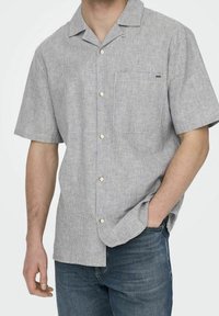 Kortärmad skjorta med knappar i grå och vita ränder, med bröstficka och platt krage, tillverkad av lättviktig tyg.