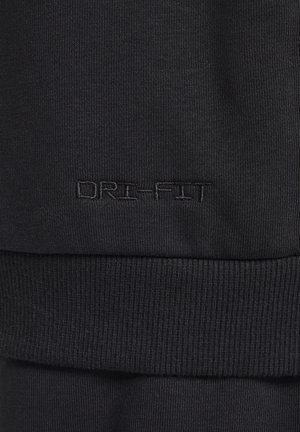 Tissu athlétique noir avec une texture côtelée. Présente le logo DRI-FIT en fil assorti, mettant en avant un design ajusté et un matériau extensible.