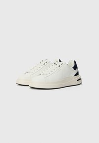 Hvite lær sneakers med marineblå detaljer, rund tå, gummisåle og kontrasterende svart såle. Har seks snorløkker og merkevare på siden.
