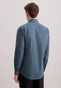 Camicia blu a motivo con piccoli disegni circolari, con polsini abbottonati e collo a punta. Il tessuto sembra liscio con una leggera lucentezza.