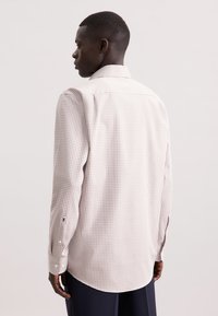 Camicia a maniche lunghe a quadri in beige chiaro con un motivo a griglia in tonalità più scure. Presenta un colletto classico e polsini con bottoni.