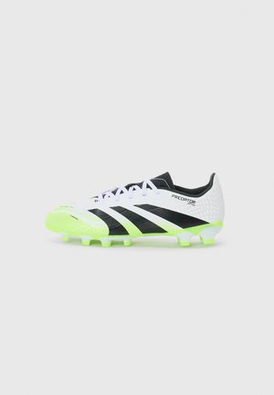 Scarpina da calcio sintetica bianca con accenti neri e suola verde neon. Presenta una tomaia testurizzata, chiusura con lacci e marchio Predator.