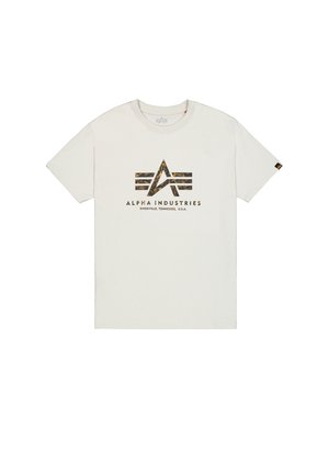 Valge puuvillane t-särk, mille keskel on logo, millel on abstraktne kuldne disain ja all musta värvi tekst "ALPHA INDUSTRIES". Lühikesed varrukad.