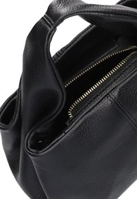 Zwart leren handtas met een korrelige textuur, voorzien van een ritssluiting met gouden hardware en een zichtbaar interieurcompartiment.