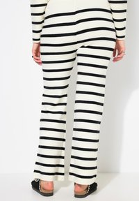 Zwart-witte gestreepte flared pants, gemaakt van een zachte tricot stof, met een aansluitende taille en een ontspannen pasvorm door de benen.