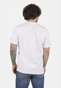 T-shirt bianco in cotone con una vestibilità ampia, maniche corte e scollo rotondo, caratterizzato da una trama liscia e senza motivi o loghi visibili.