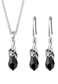 Schwarzer Kristallanhänger und hängende Ohrringe. Akzente aus silberfarbenem Metall mit filigranen Details und facettierten Oberflächen an einer eleganten Kette.