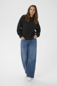 Black textured pullover with a round neckline, paired with loose blue denim wide-leg jeans and white sneakers.