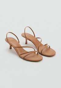 Tan-colored heeled sandals with slender straps, open toe, minimalist design, and a small wedge heel. Smooth texture, no visible patterns.