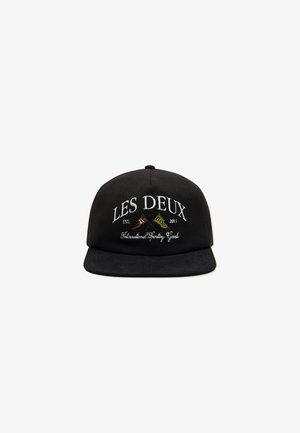 Black cap with flat brim, featuring white embroidered text: "LES DEUX EST. 2011" and "International Sporting Goods." Smooth fabric texture.