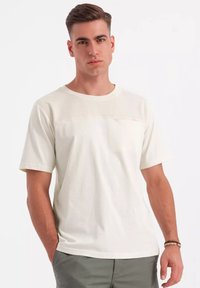 Cremefarvet t-shirt med kortærmer og en struktureret øverste panel. Lavet af letvægtsstof, med en rund hals og afslappet pasform.