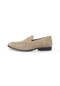 Beige Wildleder Mokassins mit genähten Details und einer niedrigen schwarzen Sohle, im Mokassin-Stil gestaltet und mit einer glatten, weichen Textur.
