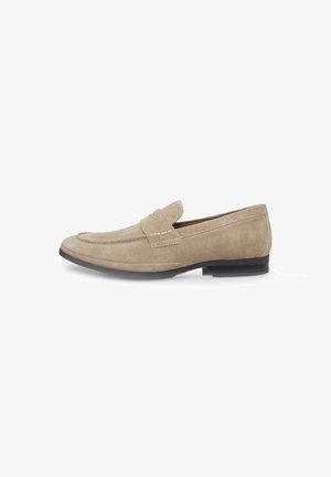 Beige suede loafers with a stitched detail and a low black sole, featuring a moccasin-style design and smooth, soft texture.