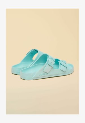 Paar hellblaue Gummi-Slides mit zwei Schnallenriemen und "JOULES"-Markenaufdruck auf beigem Hintergrund.