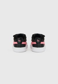 Μαύρα και ροζ αθλητικά παπούτσια Puma, με λευκές σόλες και ροζ λογότυπα Puma στις ταμπελίτσες στη φτέρνα, φαίνονται από πίσω.