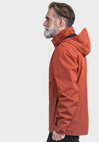 Waterdichte oranje jas met capuchon, met een gladde textuur en verstelbare manchetten. Reflecterend logo op de mouw. Zichtbare zijzakken.