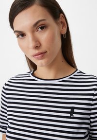 Black and white striped t-shirt with a round neckline, short sleeves, and a small embroidered logo on the left chest. Soft cotton fabric.
