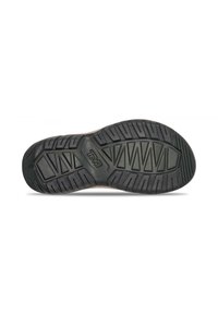 Suela de zapatilla de goma negra con un patrón de banda de rodadura texturizado, que presenta diseños angulares y un logo de la marca grabado en el centro.
