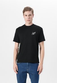 Svart bomull T-skjorte med korte ermer, rund hals, med en hvit brodert "Lacoste" logo på brystet og en rett søm design.