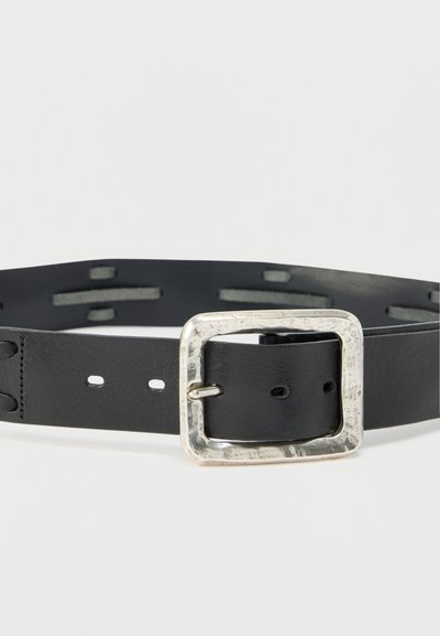 Μαύρη δερμάτινη ζώνη με ορθογώνια, υφασμένη ασημί αγκράφα, εμφανίζοντας πολλές τρύπες και ραμμένα άκρα σε λευκό φόντο.