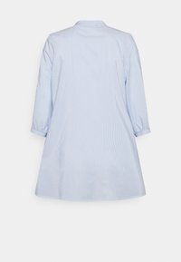Tunic azzurra chiara con righe bianche verticali, colletto e maniche 3/4. Realizzata in tessuto liscio con orlo leggermente curvo.