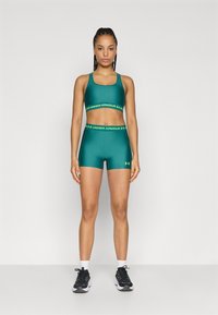 Αθλητικό τοπ σε τιρκουάζ και σορτς με πράσινο λογότυπο Under Armour. Με λεία υφή, εφαρμοστή γραμμή, συνδυασμένα με μαύρα αθλητικά παπούτσια και καλτσάκια αστραγάλου.