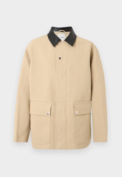 Μπεζ μακρυμάνικο σακάκι με μαύρο δερμάτινο γιακά, κουμπιά με πατιλέτα μπροστά και δύο μπροστινές τσέπες με καπάκι και ασημένια κουμπώματα.