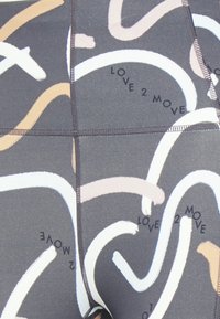 Close-up de um tecido cinza escuro com linhas curvas abstratas em bege e branco e o texto repetido "LOVE 2 MOVE" em fonte preta.