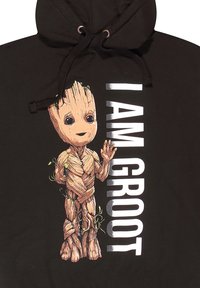 Černá mikina s kapucí, na které je kreslená postavička s texturou připomínající dřevo. Text "JSEM GROOT" je zobrazen tučnými bílými písmeny.