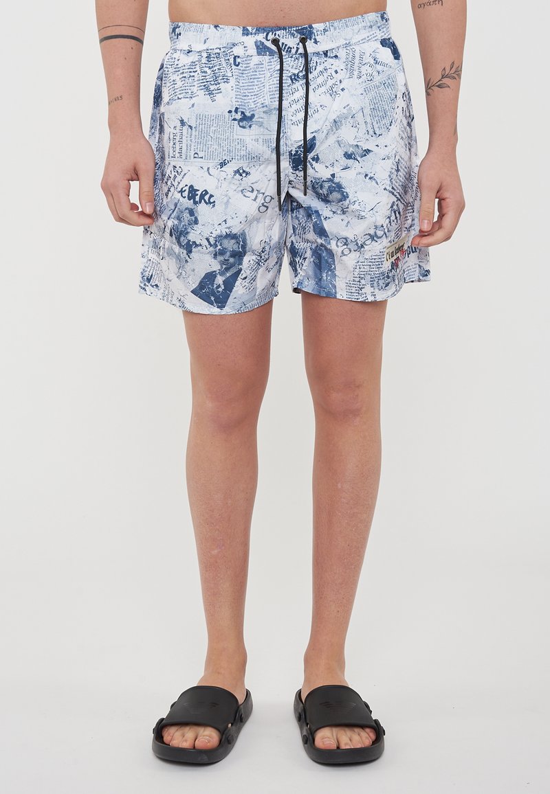 Costumi da bagno da uomo bianchi con testo blu e pattern grafici. Presentano una vita elasticizzata con cordoncino e tasche laterali.