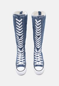 Hohe Sneakers aus blauen Canvas mit weißen Schnürsenkeln und Gummisohlen. Sie verfügen über einen langen Schaft und kontrastierende weiße Nähte.