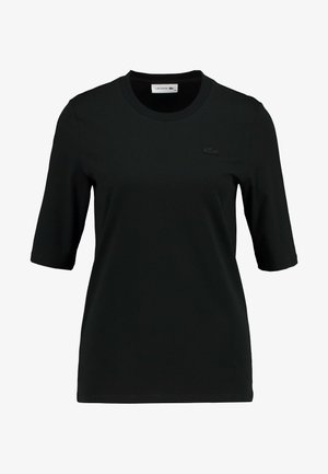Must musta T-särk ümmarguse kaeluse ja lühikeste varrukatega. Rinnal on tekstuuriga monokroomne Lacoste logo. Sile kangas.