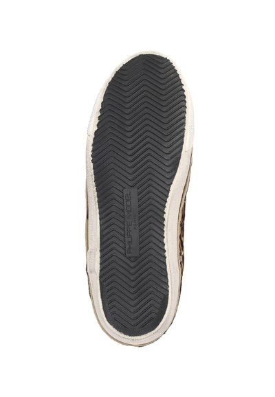 Semelle d'une basket avec un motif de bande de roulement en zigzag noir et une semelle intermédiaire blanche, comportant l'inscription "PHILIPPE MODEL PARIS" en relief au centre.