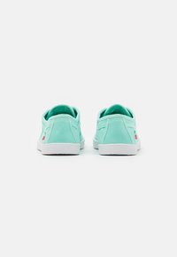 Mátově zelené plátěné tenisky s bílými gumovými podrážkami, zdobené malým červeným logem třešně na patě a jednoduchým, nízkým designem.