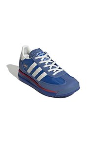 Baskets de sport bleues avec rayures blanches, tige texturée bleue, semelle en caoutchouc et accents rouges. Comprend des lacets et un col rembourré.