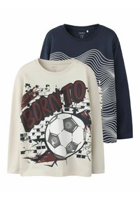 To langermede t-skjorter: én kremfarget med et fotballgrafikk og teksten "BORN TO," den andre marineblå med hvite bølgemønstre. Bomullsstoff.