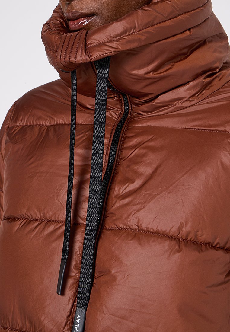 Giacca a vento marrone con colletto alto, cuciture orizzontali e zip nera con cordino per una vestibilità regolabile.