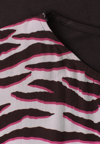 Tissu avec des rayures zébrées marron et rose sur fond violet, montrant une couture et un détail d'encolure.