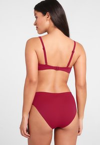 Bikini bordeaux a due pezzi con spalline regolabili, chiusura a gancio sul retro e slip alti con texture liscia.