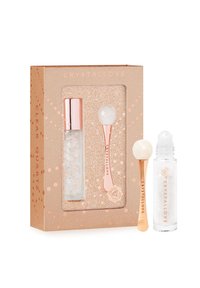 Set di prodotti per la cura della pelle in quarzo trasparente in una confezione rosa dorato. Include un rullo e una bottiglia di vetro con un tappo argentato che presenta cristalli trasparenti all'interno.