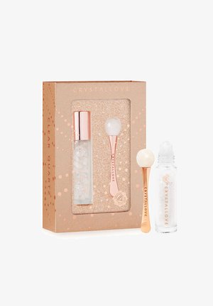 Zestaw kosmetyków z kryształu górskiego w różowo-złotym pudełku. Zawiera wałek i szklaną butelkę z metalową srebrną nakrętką, wewnątrz której znajdują się przezroczyste kryształy.
