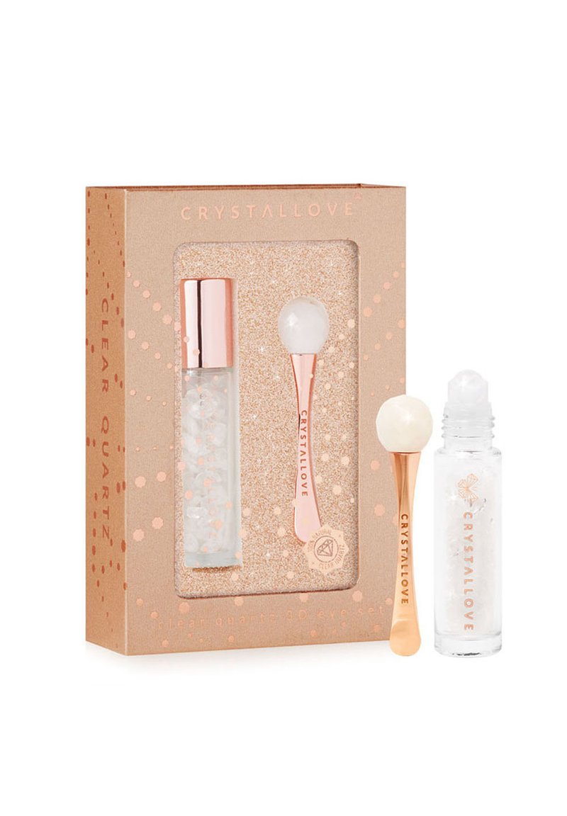 Set di prodotti per la cura della pelle in quarzo trasparente in una confezione rosa dorato. Include un rullo e una bottiglia di vetro con un tappo argentato che presenta cristalli trasparenti all'interno.
