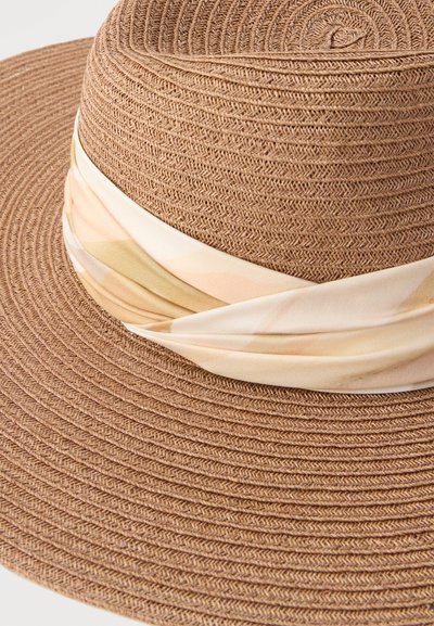 Καπέλο από πλεγμένο άχυρο με πλατιά γείσο, με μια ανοιχτόχρωμη, απαλά ριγέ υφασμάτινη κορδέλα τυλιγμένη γύρω από τη βάση της κορυφής.