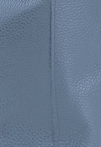 Cuir bleu texturé, présentant un motif de grain subtil. La couture visible met en valeur un design épuré et une forme structurée. Matériau durable.