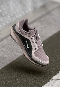 Sneaker s prešito svetlo vijoličastim zgornjim delom, črno stransko stranjo, belimi poudarki in oblazinjenim podplatom, zasnovan za udobje in podporo.