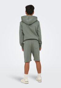 Grøn hættetrøje og matchende shorts sæt, lavet af blødt stof, med en stor hætte, elastisk talje og baglomme detalje. Casual design.