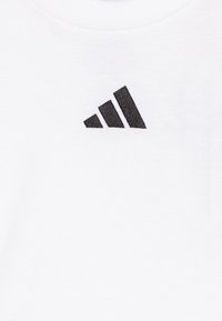 T-shirt bianco in cotone con logo Adidas ricamato nero e tre strisce inclinate sul lato sinistro del petto. Texture liscia, collo rotondo.