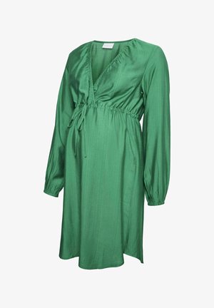 Groene jurk tot de knie van textuurstof; heeft een diepe V-hals, een cinched taille met een strik, en lange pofmouwen.