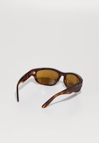 Occhiali da sole tartarugati marroni con lenti rettangolari, vetro leggermente marrone scuro e montatura elegante e testurizzata. Accentuati con il logo sulle tempie.